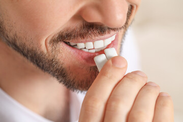 Man putting chewing gums into mouth on blurred background, closeup - obrazy, fototapety, plakaty
