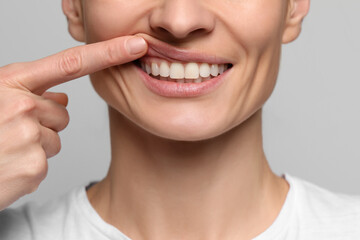 Woman showing healthy gums on light background, closeup
