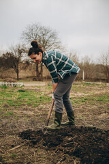 A woman is digging the earth in a field. Agricultural work in the spring in the field. Preparing the land for planting sheep in the spring.