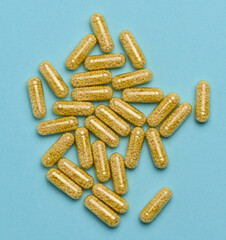 Transparent medical capsules with yellow granules inside on a blue background, tablets for...