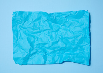 Crumpled rectangular sheet of blue paper on a blue background, top view. Place for inscription