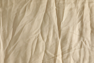 Obraz premium Crumpled beige fabric as background, top view