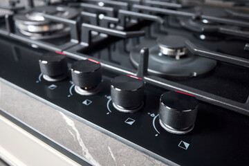 Control knobs with auto ignition selective focus closeup over out of focus black tempered glass gas...