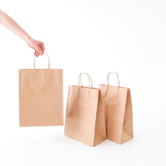 The hand reaches for a craft bag on a white background. Space for text and logo. The concept of packaging, delivery, shopping, food.