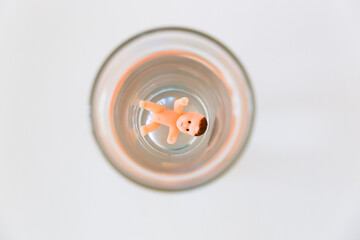 The baby is drowning at the bottom of the glass. Alcoholism leads to infertility.