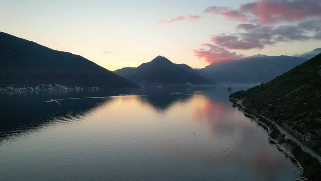 4k aerial footage of perast one of the famous tourist towns of montenegro at sunset with colorful clouds reflecting on the sea