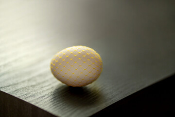 chicken egg in a decorative yellow grid on a dark background. Easter.