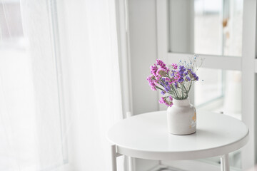 Dry flowers on the table in vase near the window. Light background with copy space. High quality photo