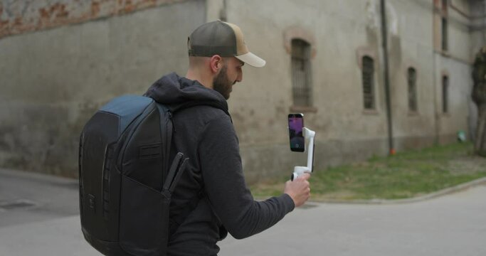 A videographer filming with a phone attached to Insta 360 Flow walking in an old place | AI-Powered Smartphone Stabilizer