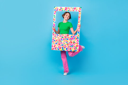 Full length photo of excited funny lady wear green t-shirt holding colorful photo frame isolated blue color background