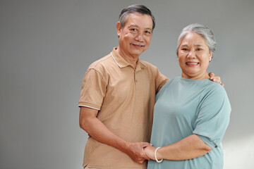 Portrait of smiling elderly couple holding hands and looking at camera