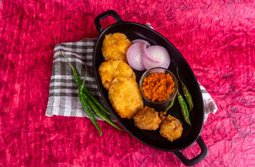 Indian Tea time snacks in group includes Veg Samosa, Kachori/kachaudi, aloo bonda, khaman dhokla, bread, onion,chilli and moong pakora/pakoda/bhaji/bhajji/Bhajiya/bajji with sauces, selective focus