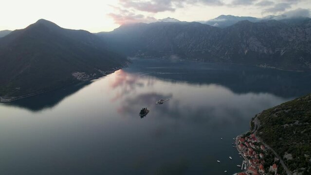 4k aerial footage of perast one of the famous tourist towns of montenegro at sunset with colorful clouds reflecting on the sea