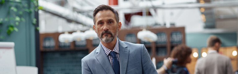 Obraz premium Portrait of mature businessman standing in modern office on colleagues background