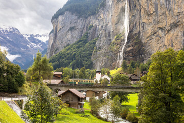 Lauterbrunnen valley with historic train elevated scenic view in switzerland with waterfall and dark clouds in late summer