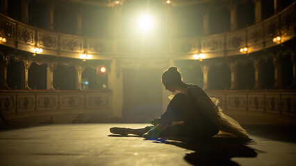 Cinematic Shot of a Young Classical Ballet Female Dancer Putting on her Pointe Shoes on a Stage of...