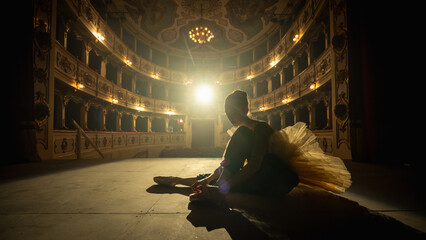 Cinematic Shot of a Young Classical Ballet Female Dancer Putting on her Pointe Shoes on a Stage of...