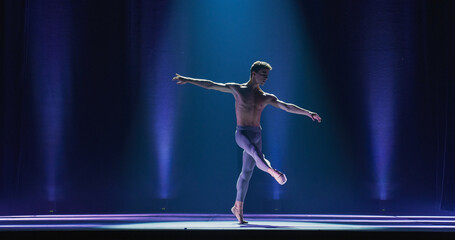 Wide Cinematic Shot of Athletic Man Dancing and Rehearsing Pirouettes on Classic Theatre Stage with Dramatic Lighting. Graceful Classical Ballet Male Dancer Performing his Choreography Professionally © Kitreel
