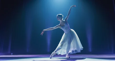 Wall murals Dance School Cinematic Shot of Ballerina in Pointe Shoes and White Tutu Dancing and Rehearsing on Classic Theatre Stage with Dramatic Lighting. Graceful Classical Ballet Female Dancer Performing a Choreography