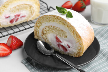 Slice of delicious sponge cake roll with strawberries and cream served on white table, closeup