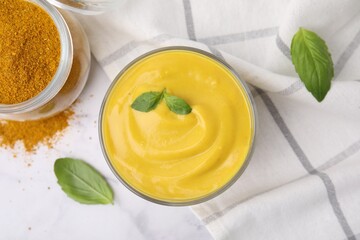 Tasty curry sauce, powder and basil leaves on white marble table, flat lay