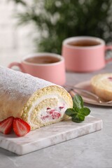 Delicious sponge cake roll with strawberries and cream on light grey table, space for text