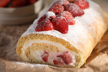 Delicious cake roll with strawberries and cream on parchment paper, closeup