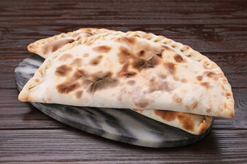 Delicious calzones on wooden table, closeup view