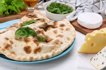 Delicious cheese calzones and products on white wooden table, closeup