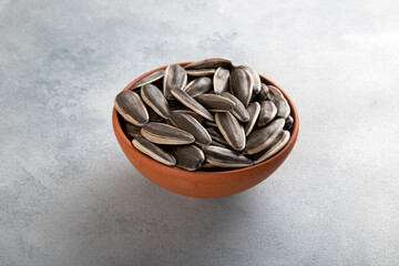 Black sunflower seeds in a bowl on light blue background,top view

