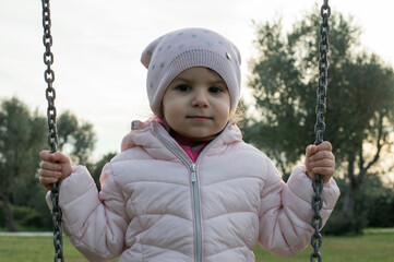 Bambina di tre anni mentre gioca sull'altalena.