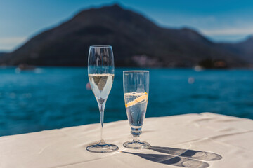 Glasses with cold drinks, a glass of champagne and a glass with a cocktail on a cafe table overlooking the lake and mountains