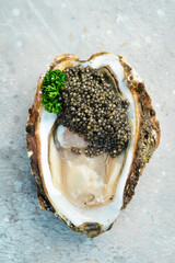 Black caviar served with oysters and lemon, on ice. On a stone background. Top view. Rustic style.