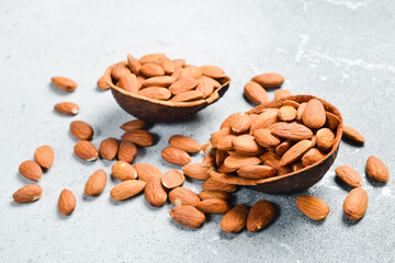 Board with bowl of almonds on a light stone background. Healthy snacks. Nuts