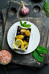Olives in a white bowl. Appetizer. On a dark stone background. Free space for text.