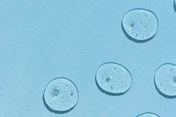 Naklejka premium Drops of serum or hyaluronic acid gel with bubbles on a blue background. Smears of cosmetic skin care products. Wellness and beauty concept