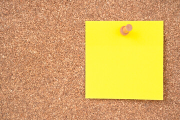 The Blank yellow sticky note paper and wooden thumbtack on wooden background.