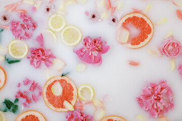 Milk bath with pink flowers, petals, lemons and oranges. Relaxation and self care