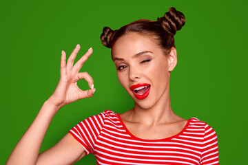 Close up portrait of happy girl with wide open mouth and wink eye gesturing ok sign isolated on vivid red background