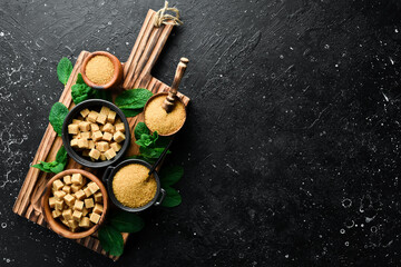 Set of brown sugar in a bowl. Set of sugar. On a black stone background. Top view.