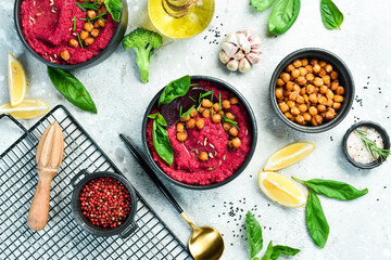Red hummus from beets and chickpeas in a bowl. Vegan recipes based on plant foods. On a concrete background.