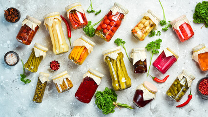 Jars with different vegetables on a stone background. Marinated vegetables. Food stocks in case of...