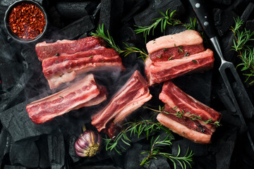 Fresh raw veal ribs with rosemary, on coals. Meat preparation, barbecue. Free space for text.