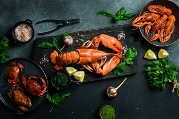 grilled lobster with lemon and basil on a black slate board. on a dark wooden table