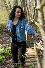 Jeune femme installant des branches de bois pour construire une cabane dans les bois