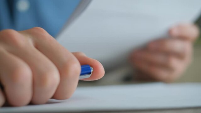 Man nervously clicking ballpoint pen button with finger while holding documents in other hand