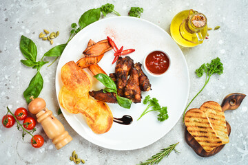 Buffalo chicken wings with sauce and potato chips on a plate, restaurant serving. Top view. Free space for text.