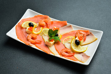 Salted salmon, shrimp and caviar with butter and lemon. Appetizer. On a dark stone background. Free space for text.