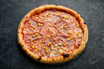 Pizza with bacon, corn and cheese. Takeaway food. Top view. On a black stone background.