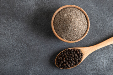 Ground black pepper with grains of black pepper on black background
